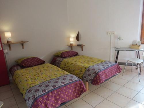 2 Betten in einem Zimmer mit einem Tisch und einem Stuhl in der Unterkunft Au Figuier des Cévennes in Saint-Germain-de-Calberte