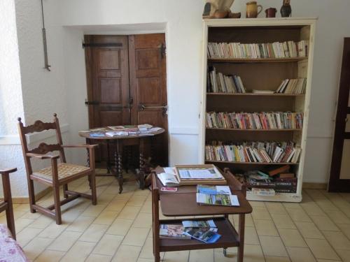 ein Wohnzimmer mit einem Tisch, Stühlen und Bücherregalen in der Unterkunft Au Figuier des Cévennes in Saint-Germain-de-Calberte
