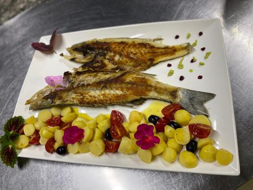 a plate of food with fish and grapes at Sunrise Hotel Orikum in Orikum