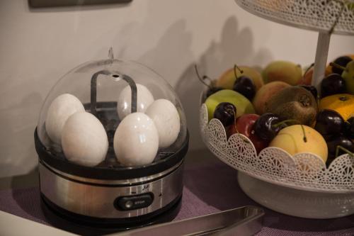 a bowl of fruit and a container of eggs on a table at Giafra Luxury Rooms in Agrigento