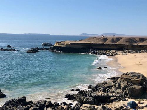 a beach with rocks and the ocean on a sunny day at Hotel K in Bahia Inglesa