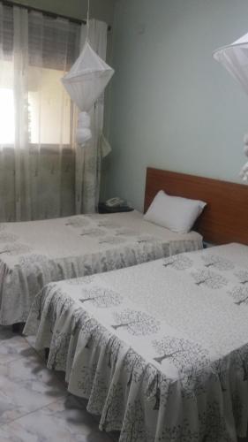 dos camas sentadas una al lado de la otra en un dormitorio en Sunset International Hotel, en Jinja