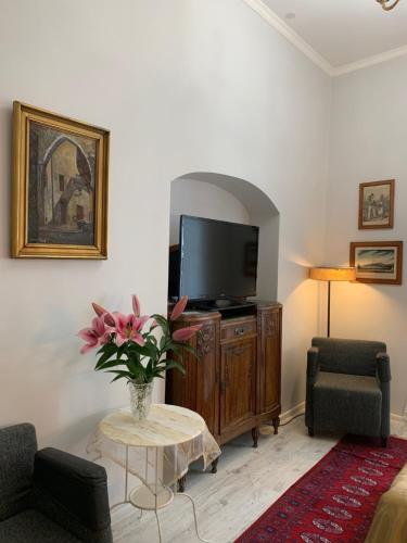 a living room with a tv and a vase of flowers at NB Apartments Riga Old Town in Rīga