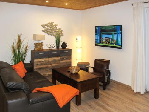 a living room with a couch and a table and a tv at Holiday Home Heide by Interhome in Altefähr