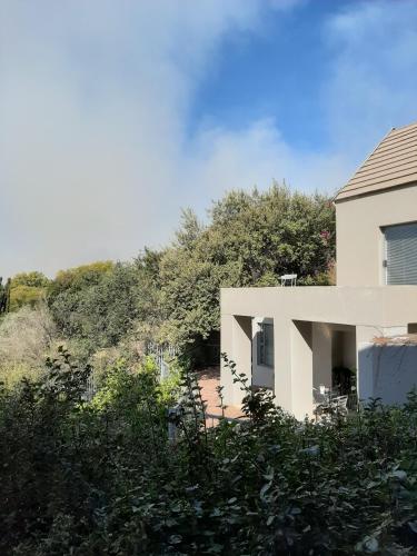 a white house with a hill behind it at Orangerie Guest House in Johannesburg