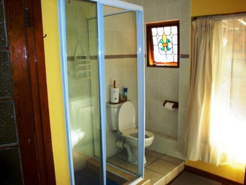 a bathroom with a toilet and a glass shower at Flintstones Guest House Durban in Durban