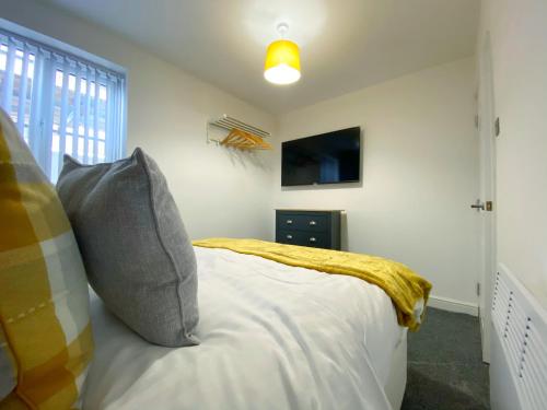 a bedroom with a bed with a yellow blanket at Kensington Suite Sasco Apartments in Blackpool