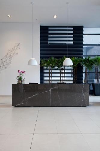 a lobby with a reception desk with potted plants at NH Collection Curitiba in Curitiba