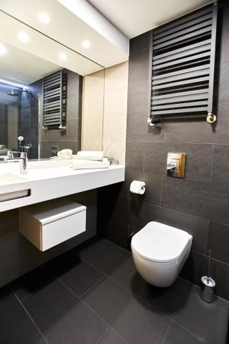 a bathroom with a toilet and a sink and a mirror at OKRA RESORT & SPA in Drawsko Pomorskie