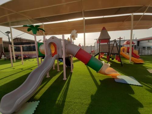 a playground with a slide on the grass at Daraysh Hotel in Sharjah