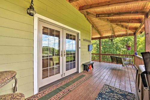 a front porch of a house with a wooden door at Charming Galax Retreat with Wraparound Deck! in Galax