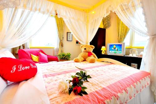 a teddy bear sitting on a bed in a bedroom at Smile Orange Homestay in Dongshan