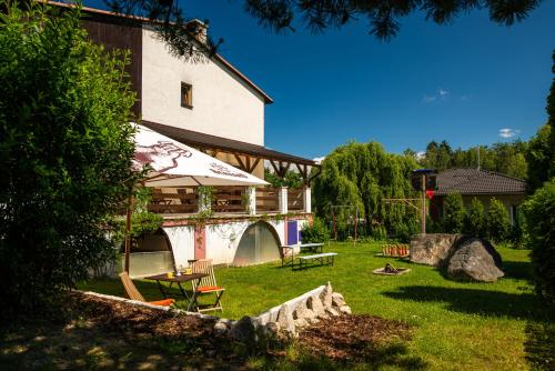 a building with a table and an umbrella in a yard at Penzion Mašek in Cheb