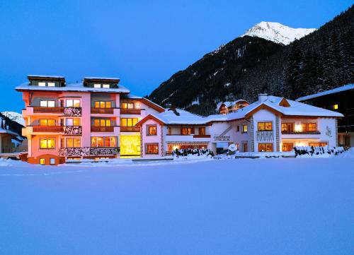 een groot gebouw met sneeuw voor een berg bij Hotel Montanara in Ischgl