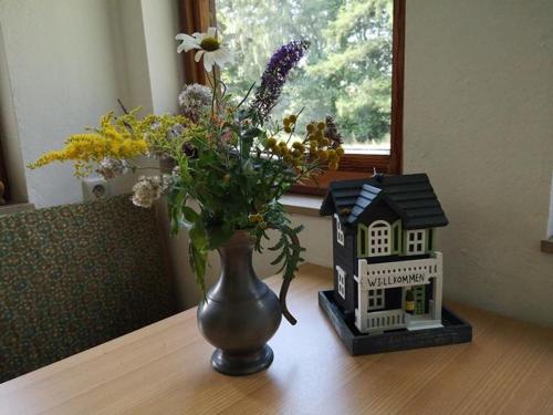 a vase of flowers on a table next to a house at Ferienwohnung Bachforelle in Neuenkirchen