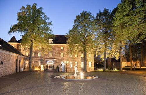 a large brick building with a fountain in front of it at Bilderberg Château Holtmühle in Venlo