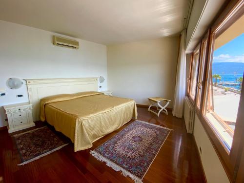 a bedroom with a bed and a large window at Camere Al Veliero in Gardone Riviera