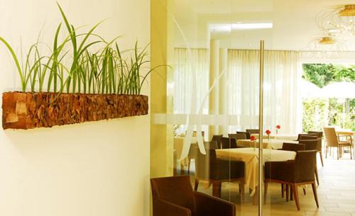 a dining room with tables and chairs and plants at Apparthotel Gartenresidence Nalserhof in Nalles