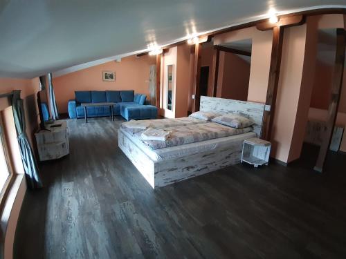 - une chambre avec un lit et un canapé bleu dans l'établissement Къща за гости Романс, à Yagodina