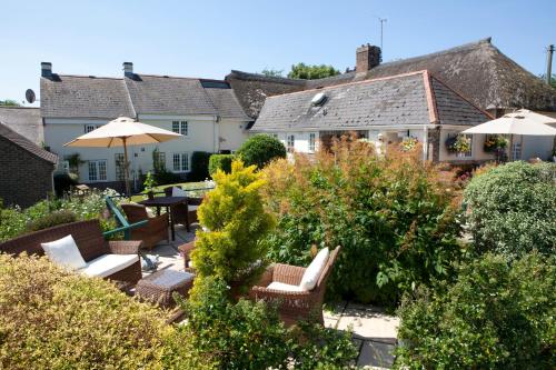 a patio with chairs and umbrellas in a garden at Yalbury Cottage in Dorchester