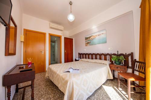 een slaapkamer met een bed, een tafel en een bureau bij Hostal Santa Eulalia in Santa Eularia des Riu
