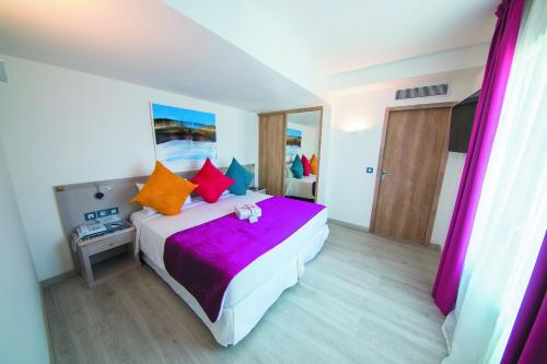 ein Schlafzimmer mit einem großen weißen Bett mit bunten Kissen in der Unterkunft Cristal Hôtel & Spa in Cannes