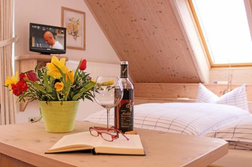 a table with a bottle of wine and a vase of flowers at Ferienhotel Mühlleithen in Klingenthal
