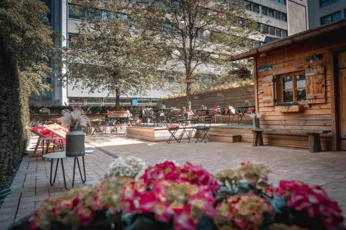 a patio with tables and chairs and flowers at Cocoon Hauptbahnhof in Munich