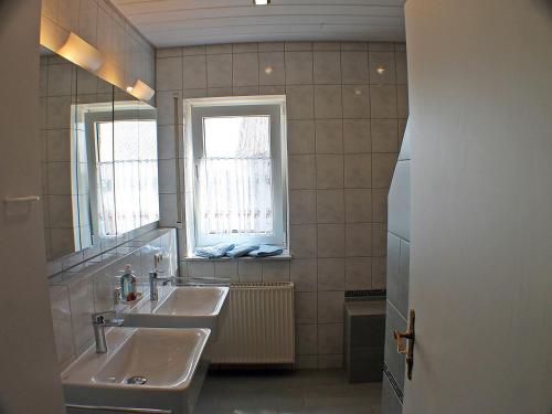uma casa de banho com 2 lavatórios e 2 janelas em Ferienwohnung Arnold Laubbach em Ostrach