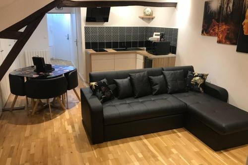 un salon avec un canapé noir et une table dans l'établissement L alysé, à Charleville-Mézières