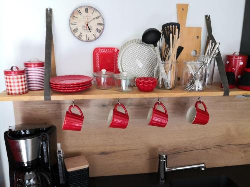 uma prateleira com utensílios de cozinha vermelhos e um relógio em Ferienwohnung Gugel em Kandern