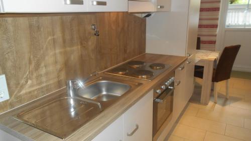eine Küche mit einer Edelstahlspüle und einem Herd in der Unterkunft Ferienwohnungen Muhr in Bodenmais