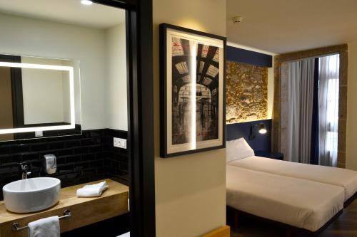 Cette chambre comprend un lavabo et un lit. dans l'établissement Hotel Alda Galería Coruña, à La Corogne