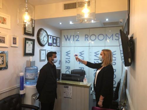un hombre y una mujer de pie en una habitación en W12 Rooms, en Londres