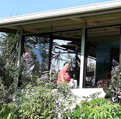 a man sitting on the porch of a house at Marita's Bed and Breakfast in Nuevo Arenal