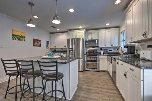 a kitchen with white cabinets and a island with bar stools at Gulfport Bungalow by Jones ParkandBeach Access! in Gulfport