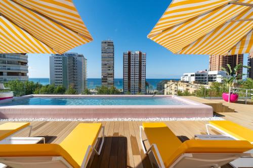 a swimming pool with yellow chairs and umbrellas at The Agir Springs Hotel by Medplaya in Benidorm
