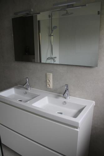 uma casa de banho com um lavatório branco e um espelho. em Huis Ter Duin em Koksijde