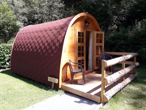 uma pequena casa hobbit com um deque e uma cadeira em La Pointe Camping em Châteaulin