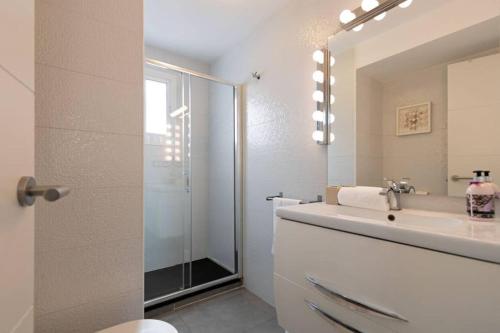 y baño blanco con lavabo y ducha. en Triana Maestro Deluxe, en Sevilla