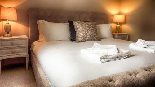 um quarto com uma grande cama branca com duas mesas de cabeceira em Ivy Cottage em Bourton on the Water