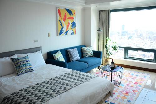 a bedroom with a bed and a blue couch and a window at Artistic Studio in Taichung