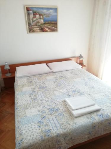 a bedroom with a bed with two white towels on it at Dvokrevetna soba s balkonom i kuhinjom in Podgora