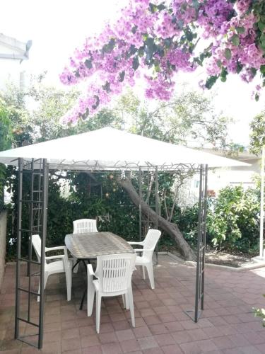 un tavolo e sedie sotto un ombrellone bianco di Dvokrevetna soba s balkonom i kuhinjom a Podgora