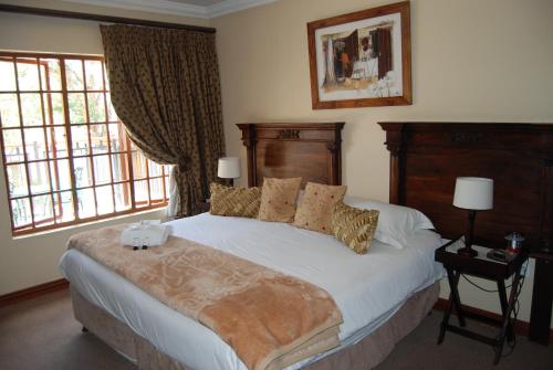 a bedroom with a large bed and two windows at Muckleneuk Guest House in Pretoria