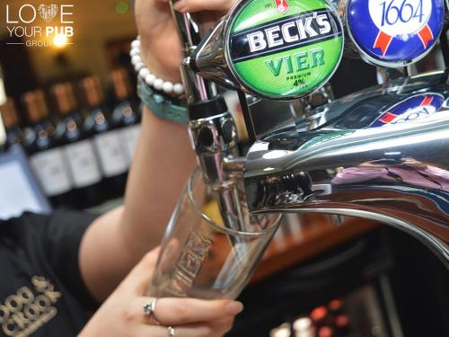 a woman is holding a glass in a bar at The Dog & Crook in Romsey
