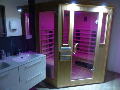 uma casa de banho cor-de-rosa com um chuveiro e um lavatório. em Dolce villa em Peyruis