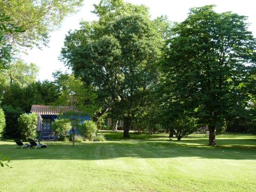 ein Park mit Bäumen und einem Haus und einem Grasfeld in der Unterkunft Les Gîtes du Domaine de Rhodes in Avignon