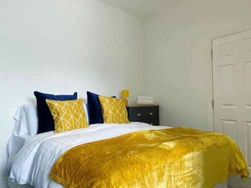 a bed with a gold blanket and pillows on it at Mayfair Suite Sasco Apartments in Blackpool