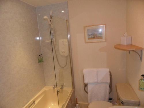 a bathroom with a shower and a toilet and a sink at Cairn Hotel in Carrbridge